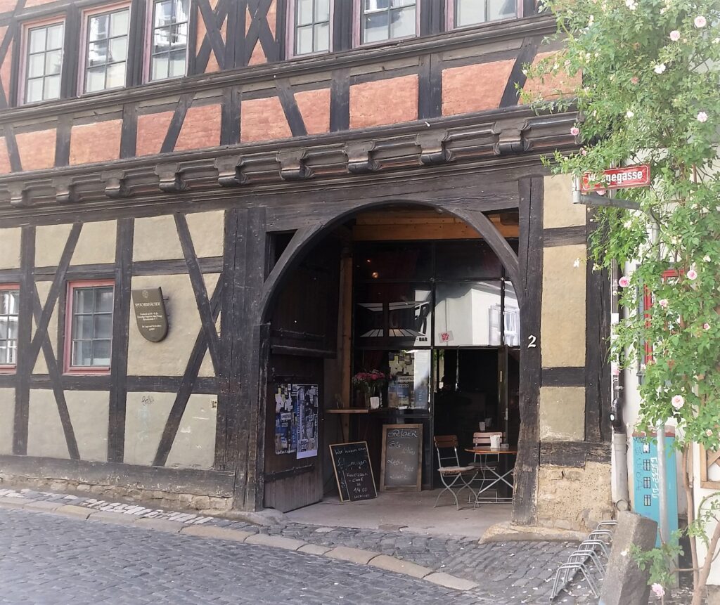 Zu sehen ist das historische Eingangstor zur Bar "Speicher" in Erfurt, sowie die Fassade des mittelalterlichen Gebäudes mit seinem Fachwerk.